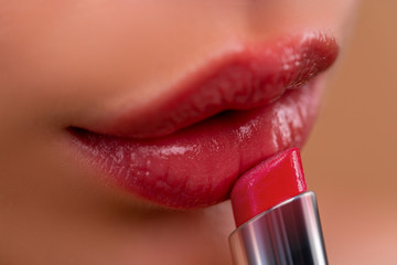 Lips. Beautiful women's lips with pink lipstick. Applies red lipstick. Sensual gloss lips make-up.