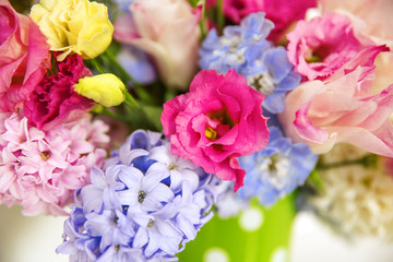 Fototapeta premium Bouquet of flowers on a shelf by the wall. Flowering branches in a bucket with a pea pattern