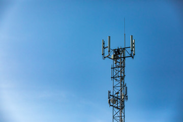 A single cellular base station is seen against a blue sky, cell tower for 3G, 4G, 5G, mobile data roaming and GPS tracking. With copy space on left