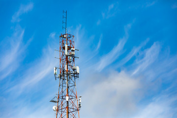 Wispy clouds are seen in the sky behind a tall pylon housing the infrastructure for mobile networks. Antenna send and receive data signals. With copy space