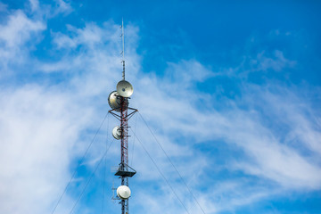 A low angle view of a cellular network base station, electronic communications equipment housed on a cable stayed steel lattice tower, with copy space