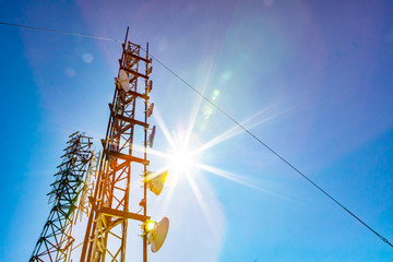 A low angle view of two mobile communication data transmitter and GPS signal towers, against a blue...