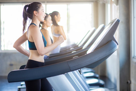 Attractive Asian Sport Women Running On Treadmil With Friend In Sport Gym