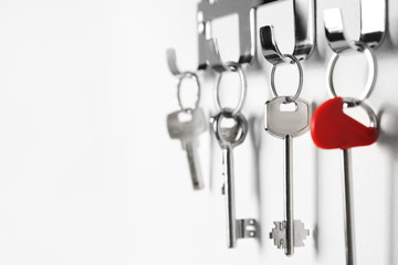 Metal key holder on light wall indoors, closeup. Space for text
