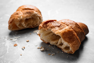 Tasty fresh croissant on light grey marble table, closeup