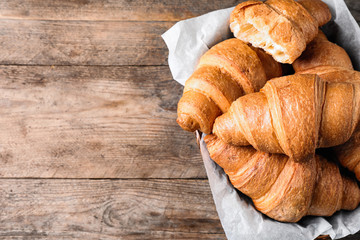 Tasty fresh croissants on wooden table, top view. Space for text