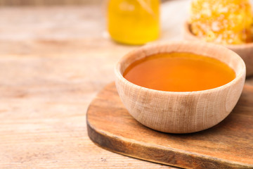 Tasty aromatic honey in bowl on wooden table