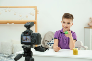 Fototapeta na wymiar Cute little blogger with slime recording video at home