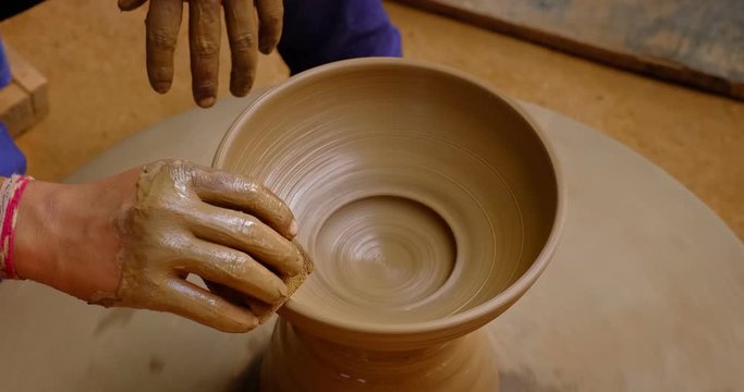 Skilled hands of potter shaping the clay on potter wheel and sculpting clay pot jar. Shilpagram, Udaipur, Rajasthan, India