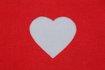 Fototapeta premium White heart made of knitted wool on a red background. Valentine's Day, February 14 Valentine's Day, a beautiful love card