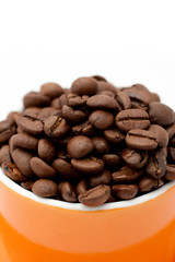 Roasted coffee beans in an orange cup