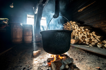 Cauldron on bonfire in a wooden house, cooking cheese