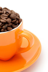 Roasted coffee beans in an orange cup