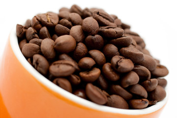 Roasted coffee beans in an orange cup