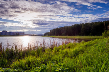 Fototapeta na wymiar Scenic view of beautiful sunset above the pond at spring evening with cloudy sky background.