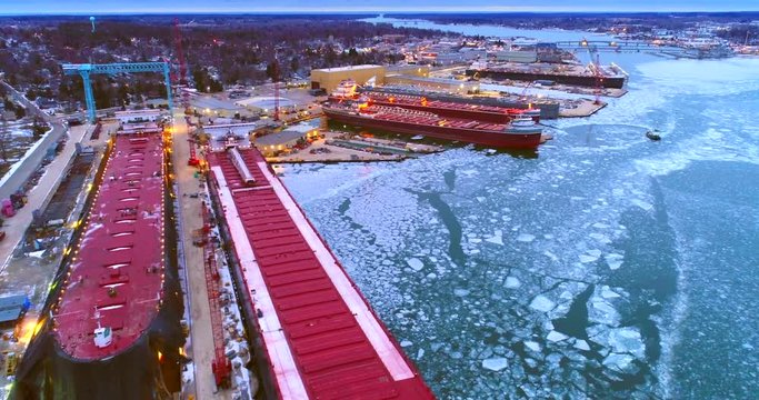 Giant Great Lakes freighter ships being built, refurbished, repaired, in icy cold waters, aerial view.
