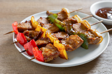 pork barbecue in a ceramic dish served with sauce on wooden table, close up. homemade style food concept.