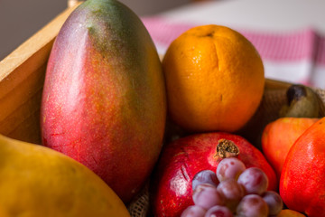 fruits in wooden basket: cashew, orange, grape, banana, mango and papaya