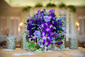Purple rose and flowers bouquet table centerpiece on wedding reception sweetheart table.
