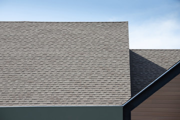 Roof shingles on top of the house against blue sky. dark asphalt tiles on the roof background. © Rattanachat