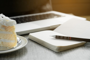 Relaxing working on cafe table with laptop notebook and a piece of cake , workplace freelance, strategies thinking