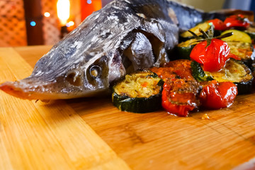 Baked sturgeon with vegetables. Delicatessen on table.