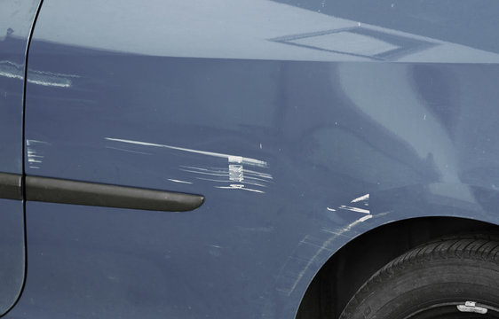 Kratzer und Dellen im Lack eines blauen-grauen Autos