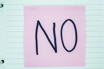 Close up black handwritten inscription "no" word on pink square stickers It's on a notebook School education objects isolated no people concept business success concept