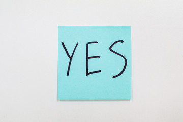 Writing on colorful sticky note Blue sticky note isolated on a white background with the word Yes Agreement and compliance concept