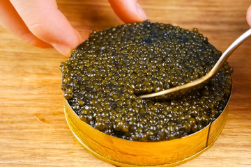 Black caviar in cardboard box. Spooning black caviar.
