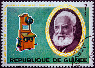 A stamp printed in Guinea shows portrait of Alexander Graham Bell and Telephone switchboard operato