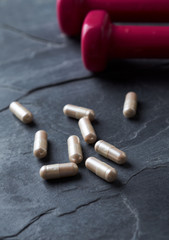 Carnitine capsules. Concept for a healthy dietary supplementation. Dark stone background. Close up.