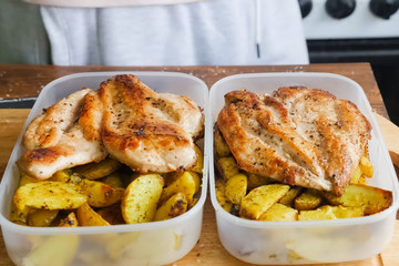 Fried potatoes with chicken breast in plastic containers
