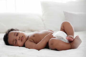 portrait of african american baby girl sleeping on white bed - obrazy, fototapety, plakaty