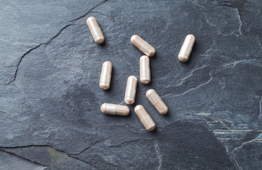 Carnitine capsules. Concept for a healthy dietary supplementation. Dark stone background. Top view. 