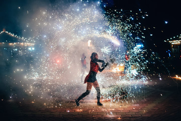 Fototapeta na wymiar Girl with fiery sparkling torches presents fire show