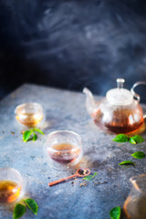 Morning light tea scene, stone table, double wall glass bowls, and a teapot