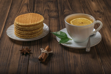 Tea with lemon and waffles with caramel cream on a wooden table.