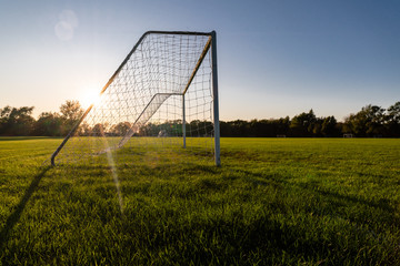 An empty soccer goal at sunset