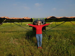 Woman portrait in front of an old aircraft. Young beautiful woman with red jacket stand in front of...