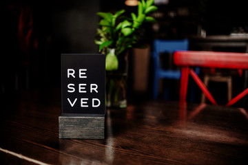 Reserved sign on a table in restaurant.Red chair and vase. Horizontal view several ojects.
