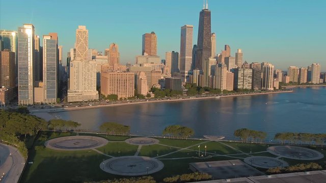 Aerial: Milton Lee Olive Park & Chicago city skyline at sunrise. USA