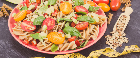 Tape measure and fresh salad with pasta and vegetables. Best food for dieting and slimming