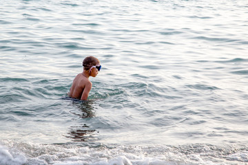 Kid swims in the sea with glasses