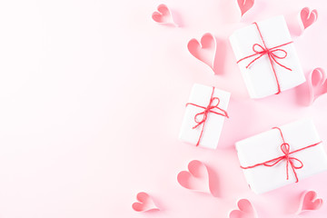 Pink paper hearts with gift box on Light pink pastel paper background. Love and Valentine's day concept.