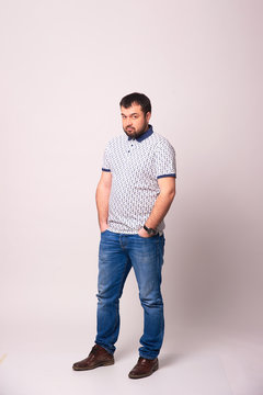 Portrait Of A Bearded Man In Loose Clothing In Full Growth On A White Background.