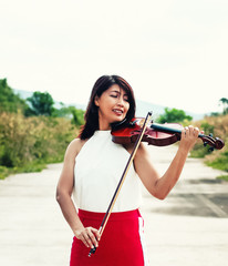 The beautiful woman playing violin ,with enjoy and happy feeling,model posing with acoustic instrumentcountry side view,blurry light around