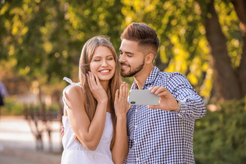 Happy engaged couple taking selfie outdoors