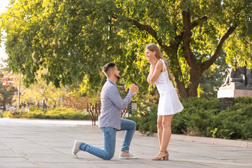 Young man proposing to his beloved outdoors