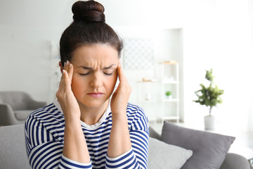 Portrait of beautiful woman suffering from head ache at home